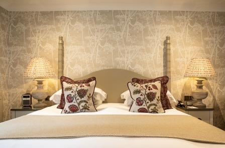 A bright and inviting living space with soft beige sofas, colourful cushions, and a centrepiece bouquet at Rothay Manor.