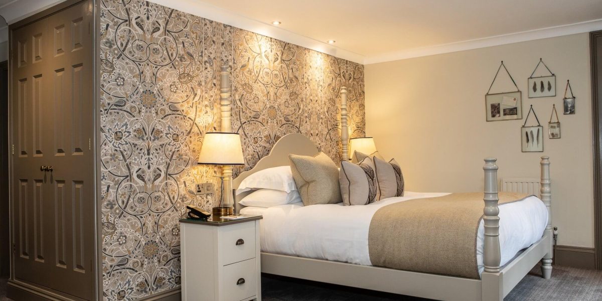 A bright bathroom with a glass shower, white tiled walls, and a window with plantation shutters at Rothay Manor Hotel.
